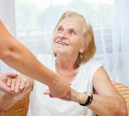 Einer alten Frau wird beim Aufstehen geholfen