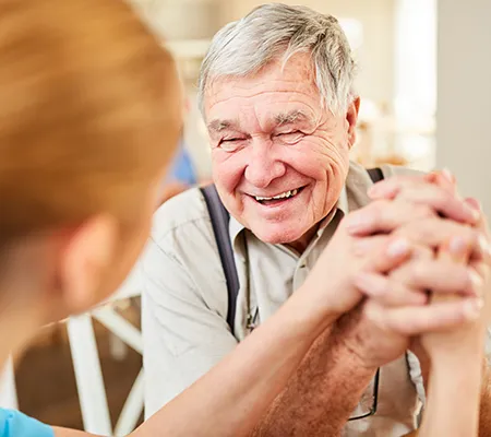 Einem älteren Mann wird die Hand gehalten