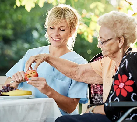 Ältere Dame bekommt einen Apfel geschnitten